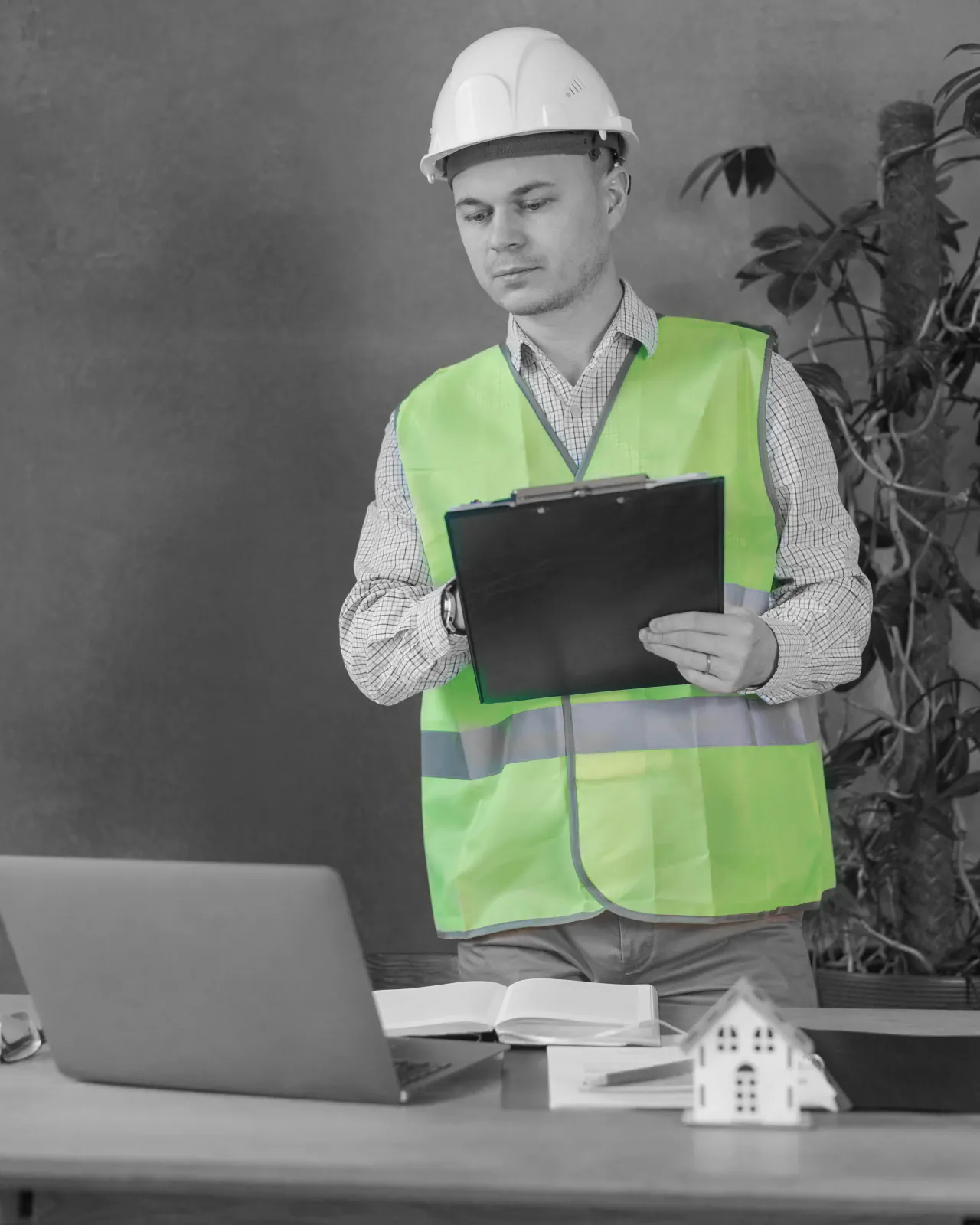 An engineer reviewing plans in the office with a laptop