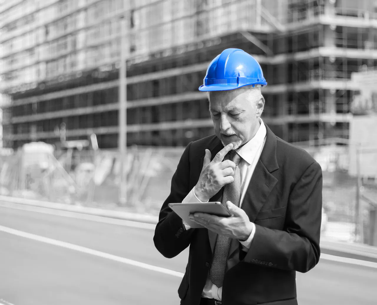 Construction manager in a hard hat reviewing a tablet on site