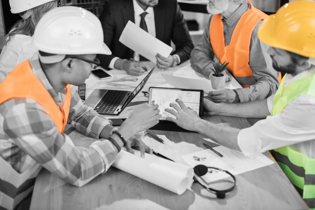 A site team around a table with drawings, laptops and a tablet