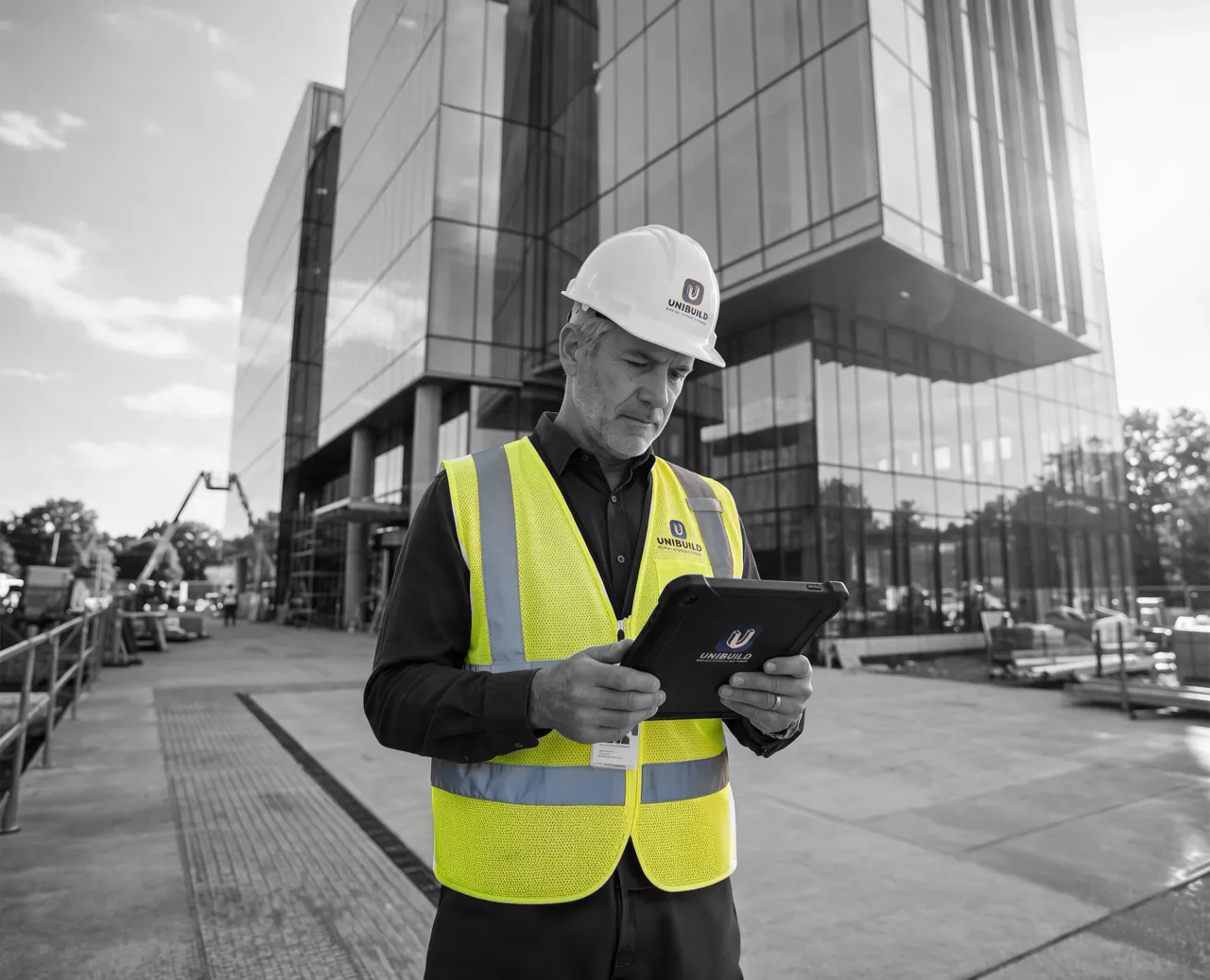Construction worker in a high-visibility vest reviewing a purchase order on a tablet