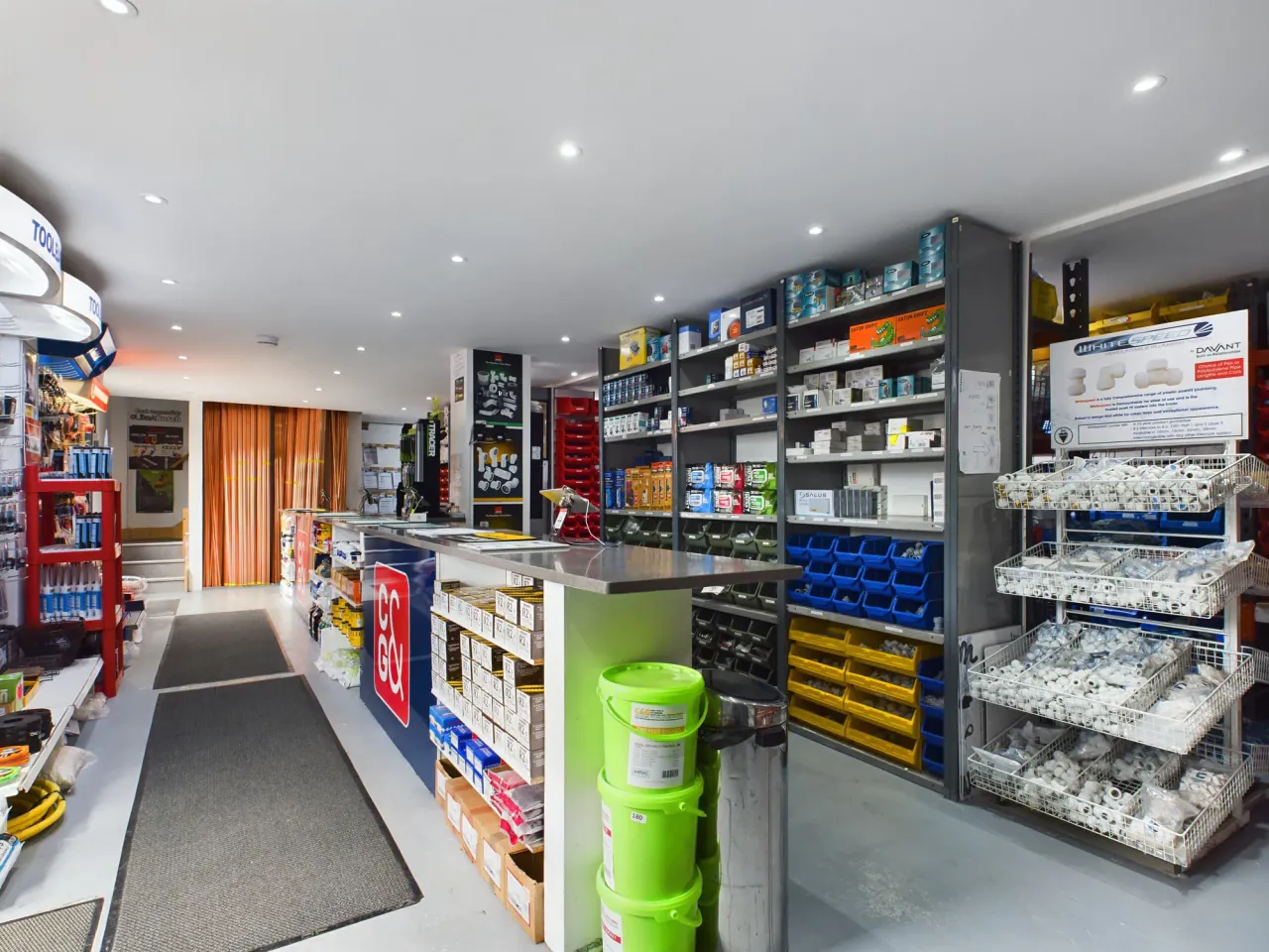 Colour-coded picking bins of plumbing fittings behind the C&amp;G trade counter in Erith, with push-fit fittings racked alongside