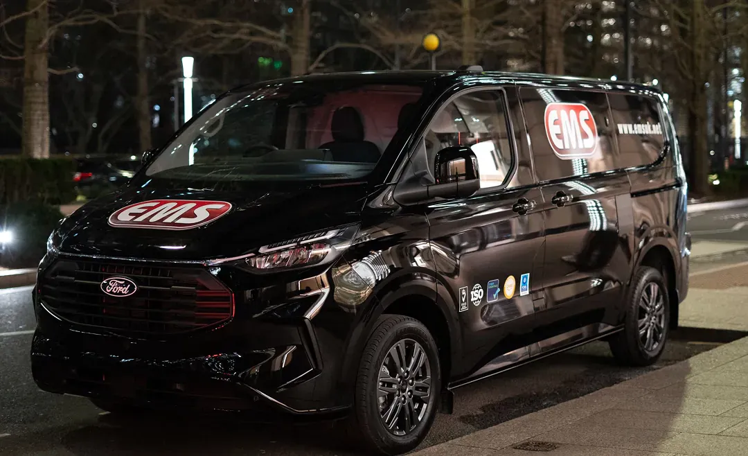 An EMS Ford Transit Custom at night, with the company mark on the bonnet and the side