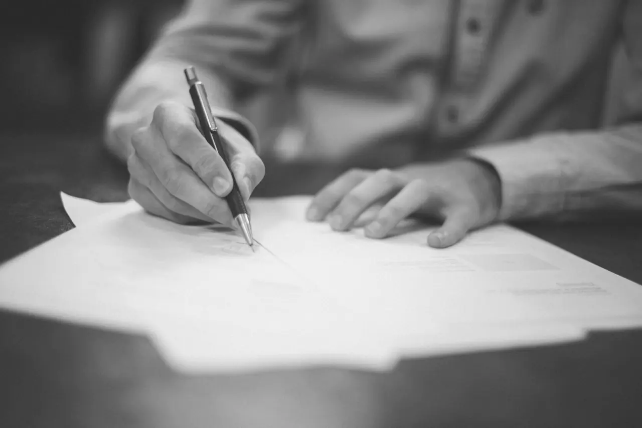 A hand writing on documents at a desk
