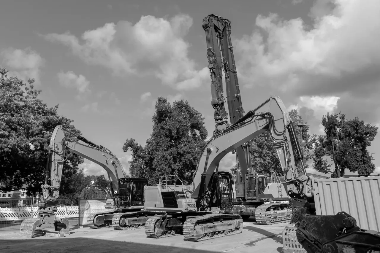 Tracked excavators standing on a site among mature trees