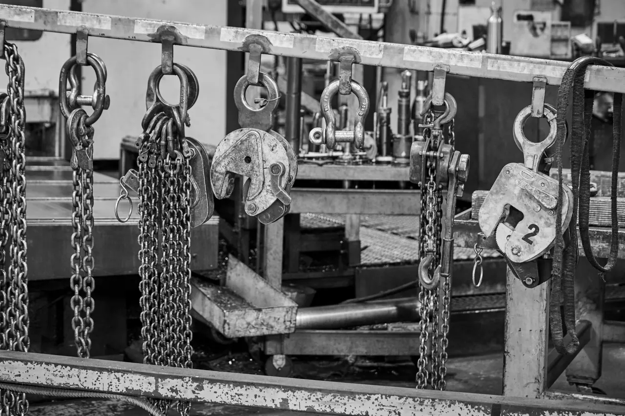 Lifting chains, shackles and plate clamps hung on a rack in a workshop